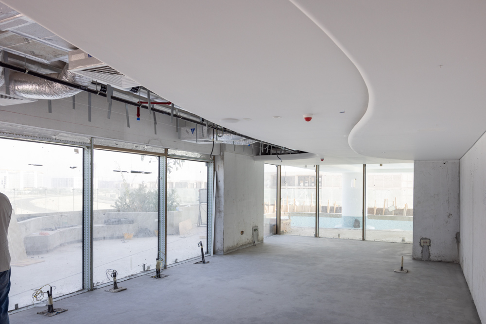 Beach Walk Residence A spacious, unfinished interior with a curved ceiling and large windows providing natural light.